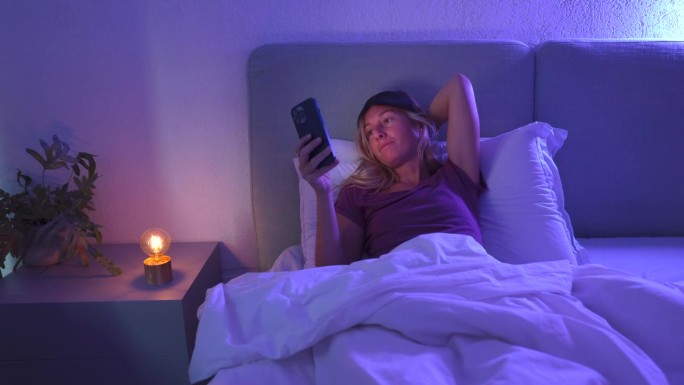躺在床上睡不着的女人用手机，她睡不着