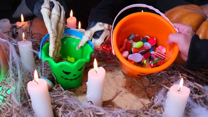 秋季节日万圣节的节日背景一个男人骷髅服装显示糖果收集在桶里，不给糖就捣蛋。