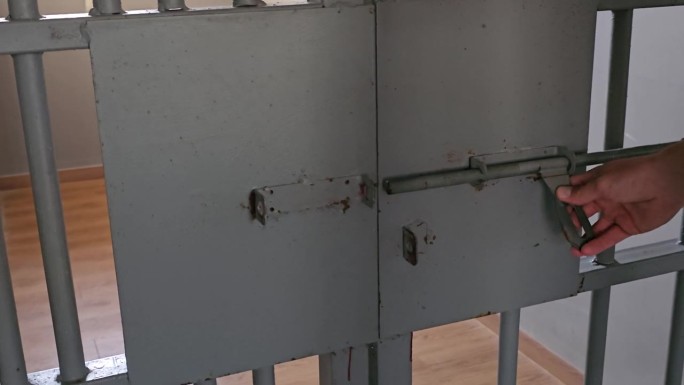 男子用手锁、闩锁、滑桶来关闭牢房的门——特写