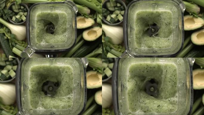 头顶慢镜头，搅拌机混合绿色蔬菜排毒汁与芹菜，鳄梨和茴香
