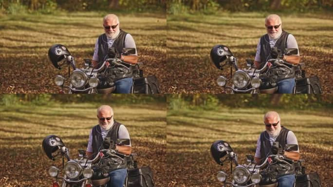 高级白人男性骑摩托车的人坐在摩托车上，戴着耳机用手机视频通话