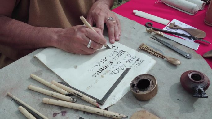 一个人用古罗马工具在羊皮纸上写字的手