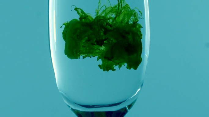 绿色的液体漂浮在玻璃杯里的水中形成云