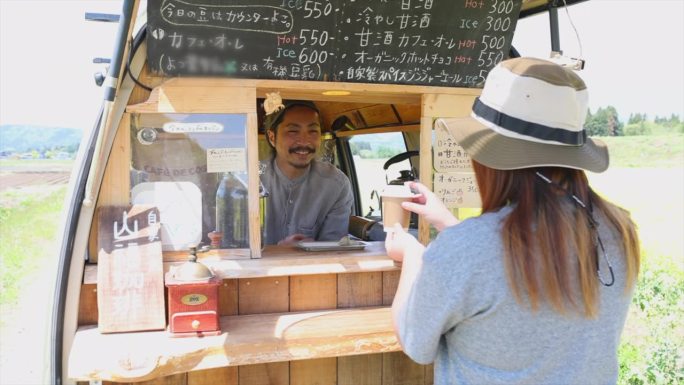 一名日本男子在乡下用油菜花开着面包车卖咖啡