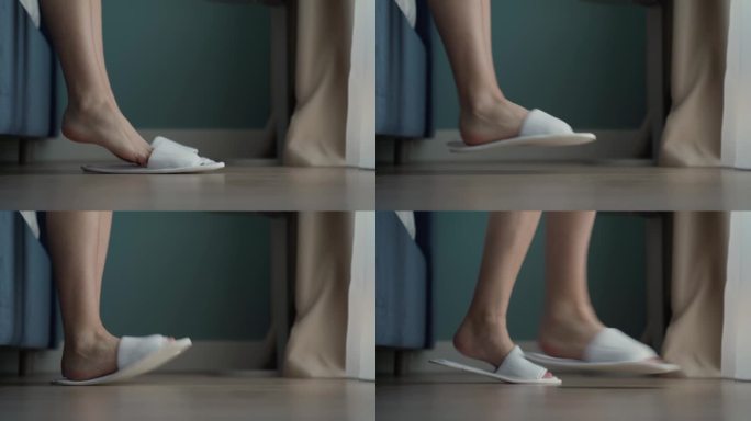 一个女人穿上白色拖鞋，从酒店房间的地板上爬起来。客人把脚穿上拖鞋，下床，离开特写镜头