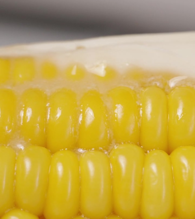 垂直视频。一块黄油在热玉米棒上融化了。这是一个特写镜头。