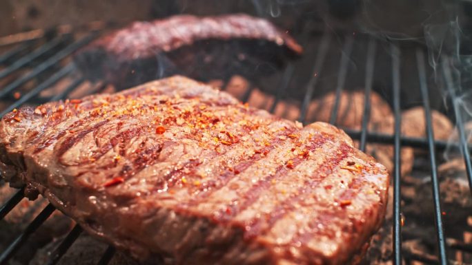 香料混合物落在烤肉架上的牛排上