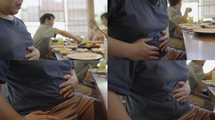 一个身材高大的男人因为吃得太多，肚子疼得很厉害，他的朋友们在一家日本餐馆享受午餐。