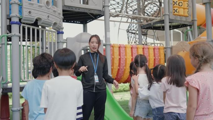 多元文化儿童在学校操场与女老师一起享受户外游戏。