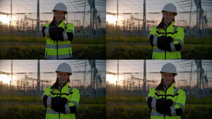 夕阳下，电站里微笑的女电气工程师双臂交叉的画像。从事电塔翻译工作的女电气工程师。