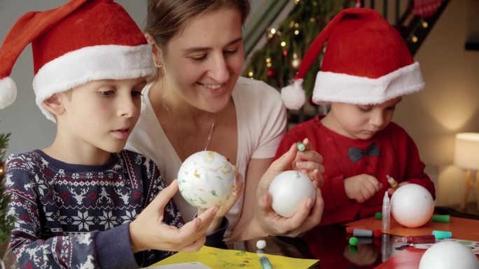 年轻的母亲带着两个孩子为圣诞节做准备，手工制作装饰品。寒假，家人团聚，孩子和父母一起庆祝