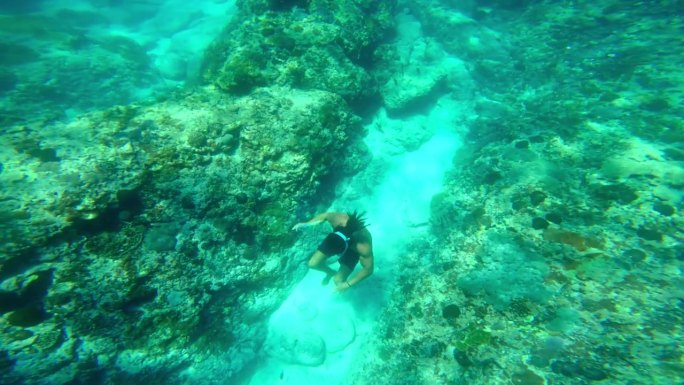 男子在蓝色的海底浮潜游泳。和一个人在海水里自由潜水。在深海中浮潜和潜水。浅水中的海洋生物。在珊瑚礁附