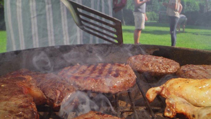 在一个阳光明媚的花园聚会上，烤肉被放在烤架上