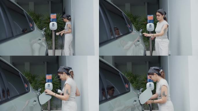 户外拍摄的亚洲女性旅行者走到她的电动汽车，插上电源充电。