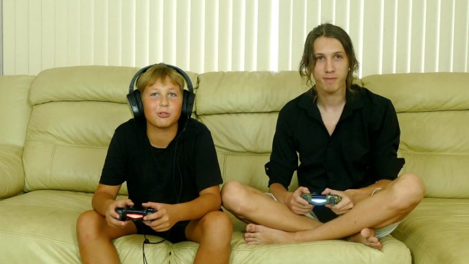 兄弟俩在家里的沙发上玩电脑游戏