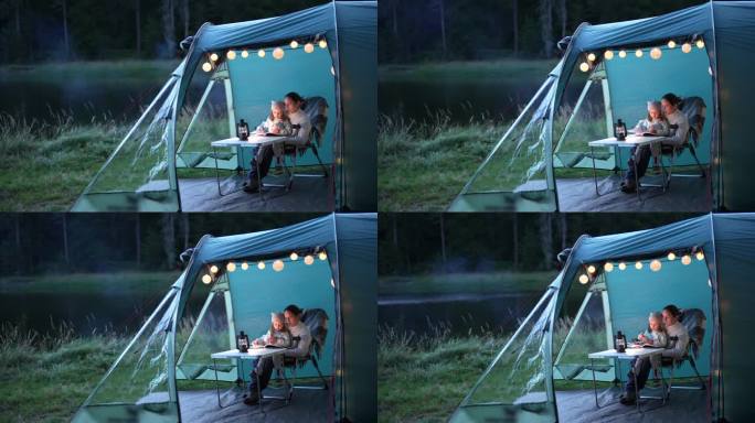 一家人在湖边露营。和妈妈在帐篷里讲睡前故事。