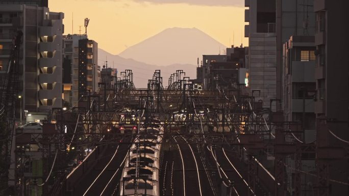 日本日落时分，火车行驶在铁轨上，背景是富士山。日本交通，亚洲通勤生活方式，亚洲旅游