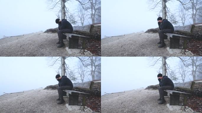 在雾蒙蒙的早晨，一个忧郁的人独自坐在湖边的长凳上