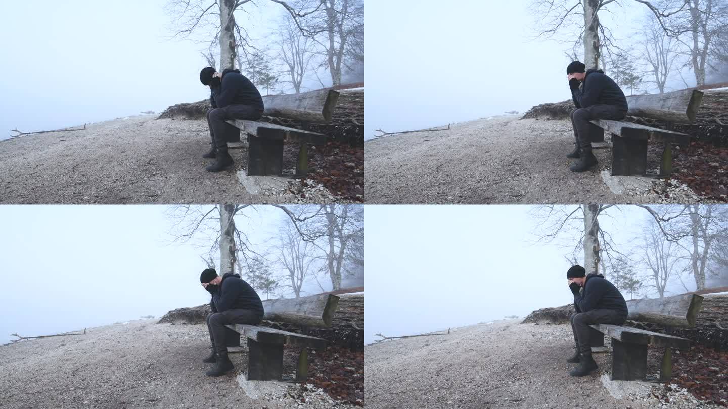 在雾蒙蒙的早晨，一个忧郁的人独自坐在湖边的长凳上