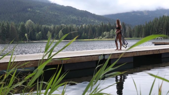 年轻女子沿着湖上的木码头散步