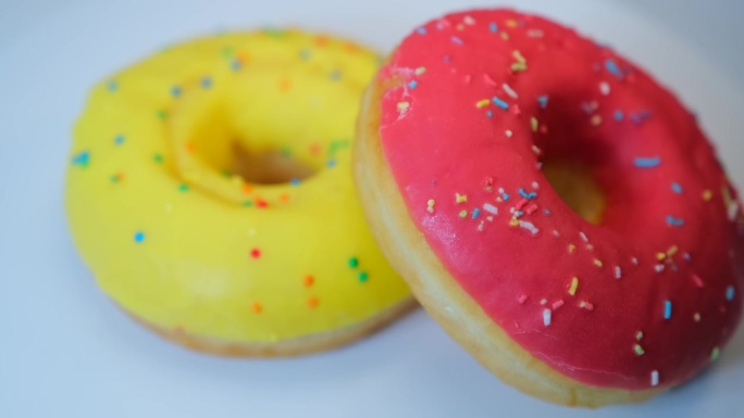 美味的甜甜圈背景，黄色和粉红色的釉和彩色的糖屑，草莓和香蕉口味