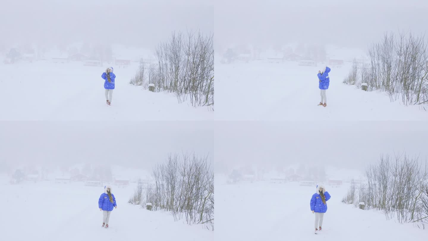穿着蓝色外套的女人欣赏真正的冬季童话，在大雪中漫步在斯堪的纳维亚村庄