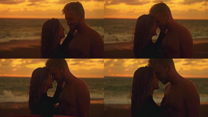 夕阳下，一对深情的冲浪夫妇在海滩上面对面。宁静，热爱冲浪夫妇拥抱面对宁静的海洋海滩在日落时分，享受夏