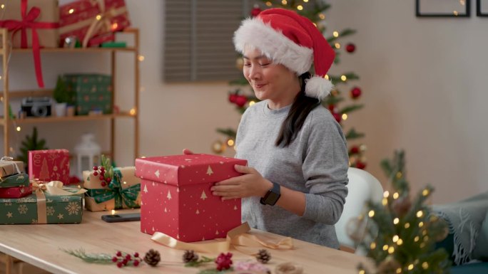 圣诞节当天，亚洲女性在家里办公室打开礼盒，惊喜不已。