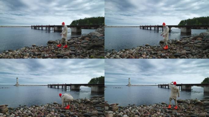 年轻的成年男子独自站在海边，在清晨向水里扔鹅卵石