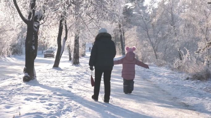 冬日里，奶奶带着孙女在雪地里散步。家庭时光快乐。美丽自然