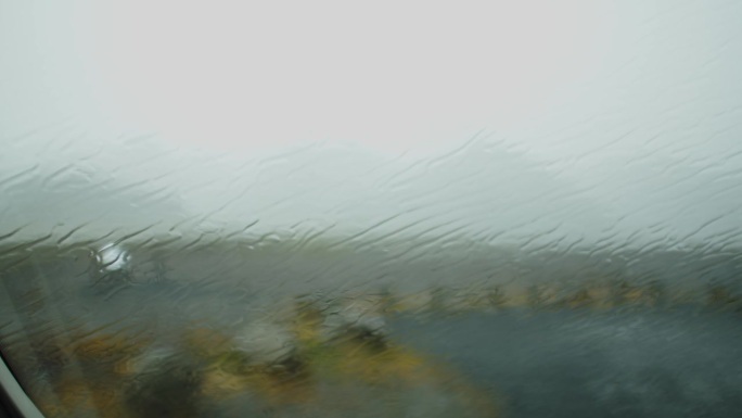 大雨落在车窗上。这辆车停在冰岛荒野的一个停车场上