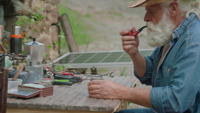 退休老人一边抽烟一边修理坏了的太阳能电池板