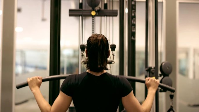 专注的三角肌训练:意志坚定的运动员在健身房的专用机器上进行高强度的三角肌训练。
