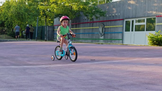 小男孩用学习轮学骑自行车，角度低