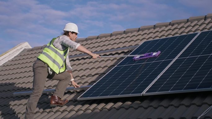工程师清洁屋顶太阳能板，维护和可再生能源或电力。技术员，人拖地光伏电池和灰尘、污垢和提高性能，电力生