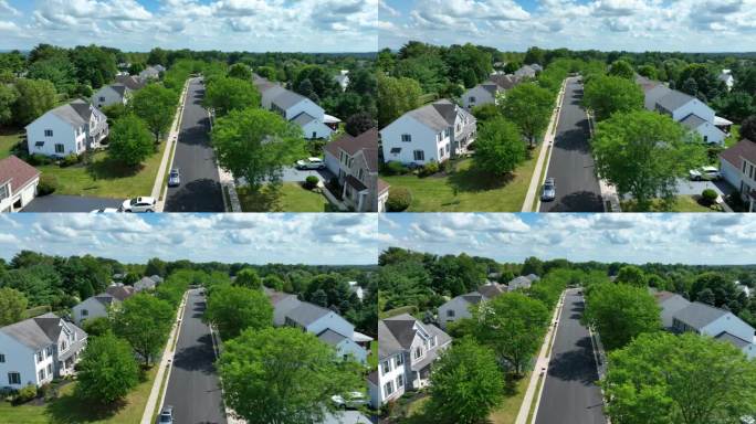 夏天的美国社区。住宅开发街道上的空中飞行，两旁是成熟的树木和大型家庭住宅。