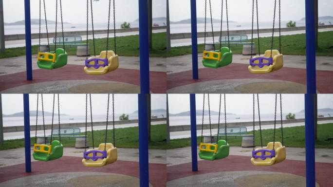 在海滨公园空无一人的儿童游乐场里，五颜六色的安全塑料秋千挂在金属链上