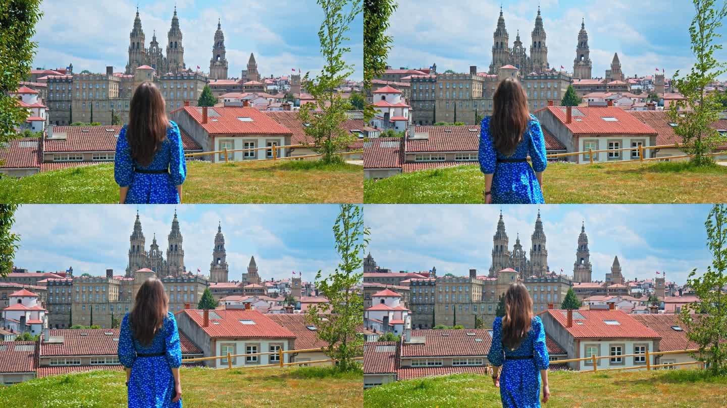 一个旅游女孩看着圣地亚哥德孔波斯特拉大教堂，俯瞰西班牙的城市全景。