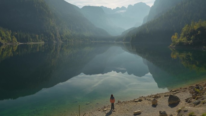 一个腿部受伤的女人在湖边散步，看着岣梢湖和山脉的景色