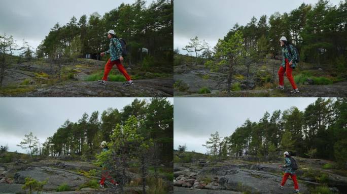 在挪威背包旅行，年轻的女旅行者走在美丽的松林附近的大石头上