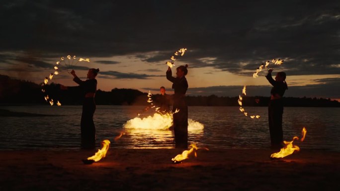 日落后河滩上惊人的火焰表演，慢镜头，年轻女士旋转火把