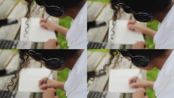 一个大学生在她的笔记本上写着东西，从肩膀上看过去