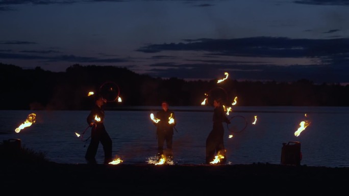 夏夜，马戏演员在河岸上表演火种，电影慢动作
