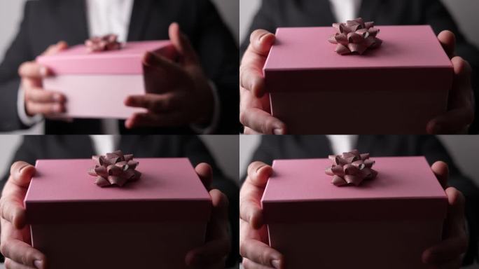 一个男人递给观众的粉色礼盒