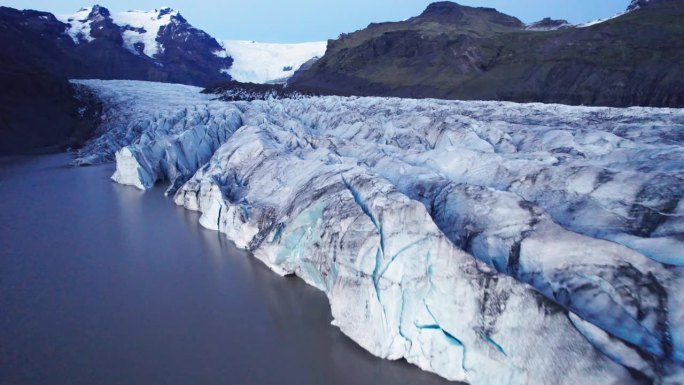 航拍:冰川蜿蜒的路径上有深深的裂缝和锯齿状的冰层，这是气候变化对这一自然奇观不断移动和转变的影响的证