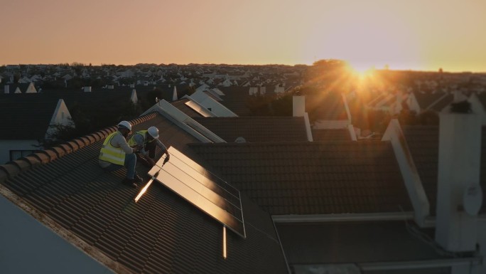 房屋，屋顶太阳能电池板和人们在光伏板，可持续生态电网或可再生能源上的团队合作。小区夕阳、绿色供电和工