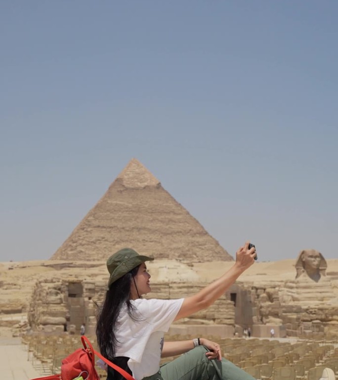 埃及，开罗，亚洲女游客拍摄吉萨大金字塔的背景