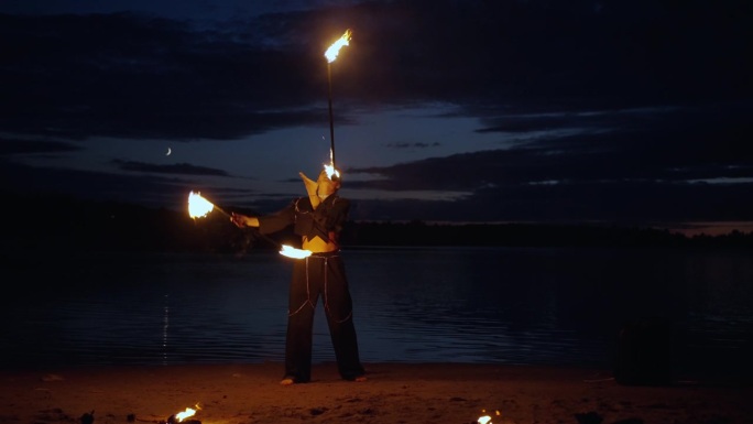 专业的马戏团女演员在夜晚的湖岸上耍耍燃烧的火炬