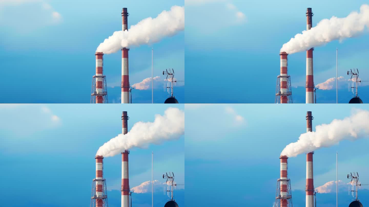 两个热电站的烟囱在蓝天上冒着白烟。供暖，电力生产，能源危机，环境问题。