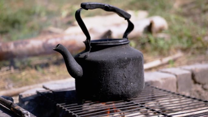 煤烟中的旧黑水壶在大自然的烟雾中被火加热，特写
